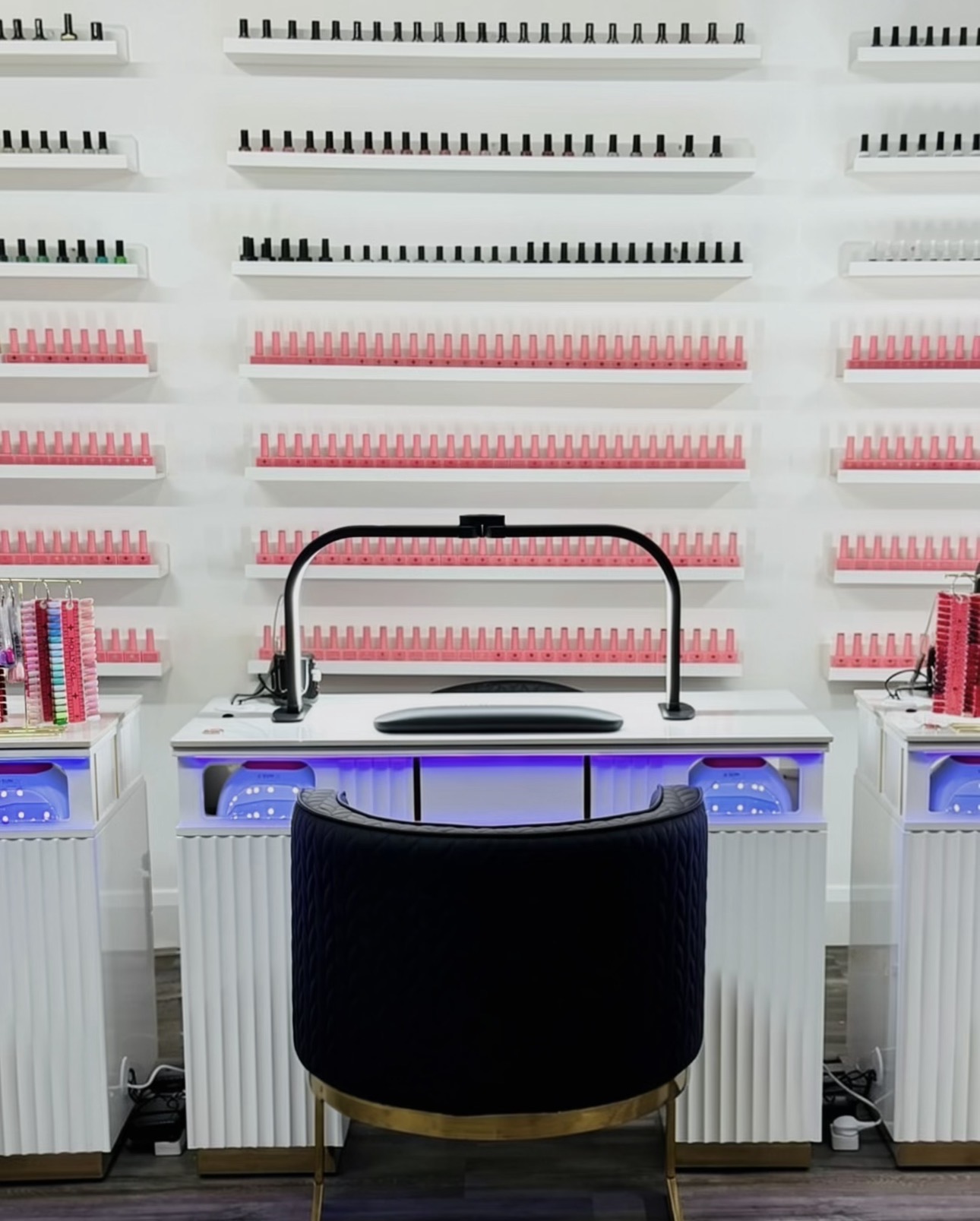 Vela Studio Galway nail station with a white manicure table, lamp and dark chair in front of a wall of polish